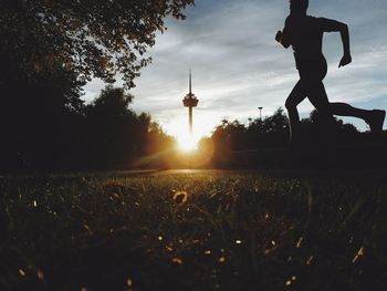 Surface level of silhouette man running on land against sky during sunset