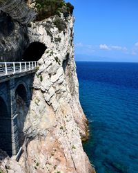 Rock formation by sea against sky