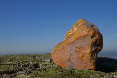 Close-up of rock on land against clear blue sky