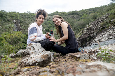 Two women enjoying drinking mate together while relaxing outdoors in the nature.