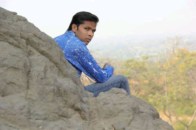 Side view portrait of a young man on rock