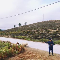 Rear view of man photographing on mountain against sky