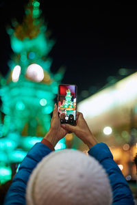 Rear view of woman photographing with smart phone at night