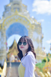 Portrait of young woman wearing sunglasses while standing outdoors