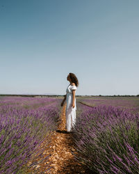 Rear view of woman standing on field against clear sky