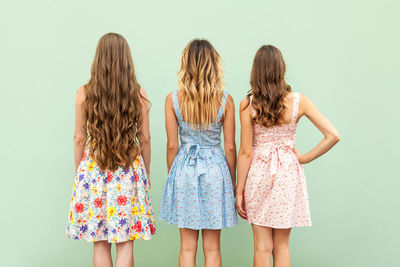 Rear view of women standing against white background