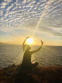 People standing in sea against sky during sunset
