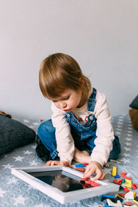 Child plays at home an educational game with a multi-colored magnetic puzzle