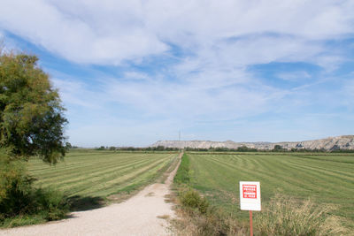 Road amidst field against sky