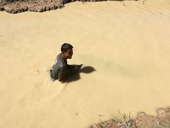 Full length of young man on horse in sand at beach