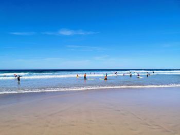 People on beach against blue sky