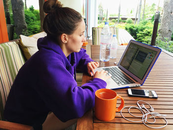 Concentrated woman using laptop at wooden table