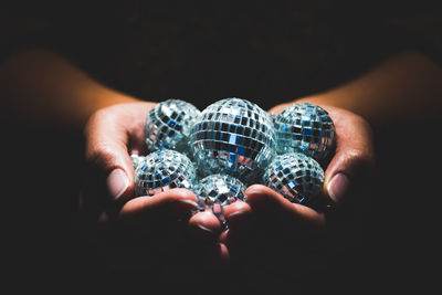 Close-up of woman holding shiny balls in darkroom
