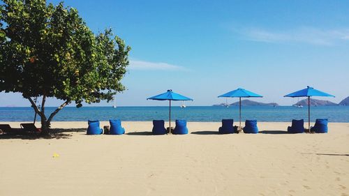 Parasols and seats at beach against sky