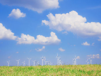 Wind turbines on field against sky