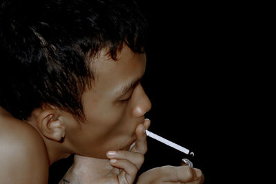 Close-up portrait of boy making face against black background
