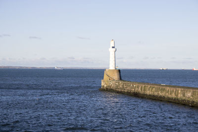 Lighthouse by sea against sky