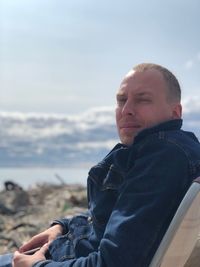 Portrait of man sitting on chair against sky