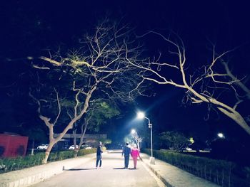 People walking on illuminated street at night