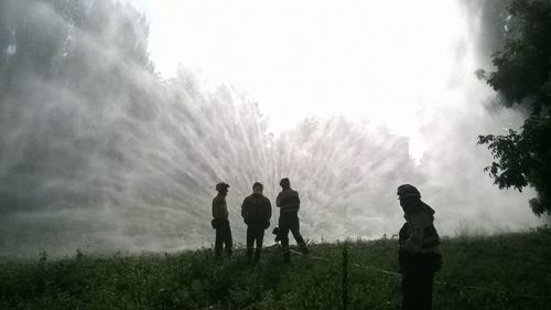 Firefighters on field against sky