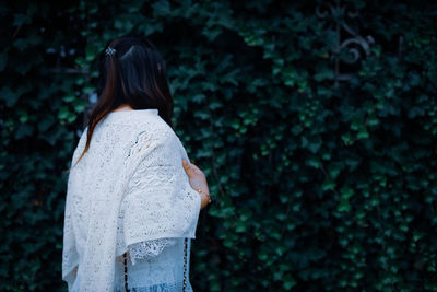 Rear view of woman standing against plants