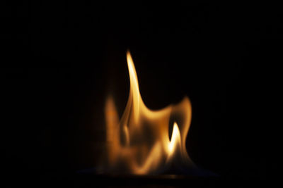 Close-up of burning candle against black background