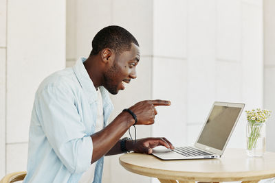 Side view of man using laptop at home