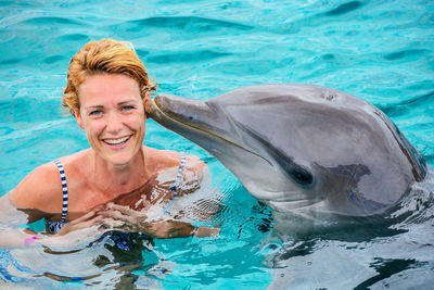 Portrait of smiling woman with dolphin swimming in sea