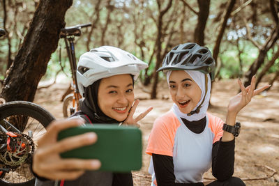 Smiling young females taking selfie at forest