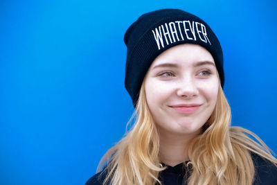 Close-up of smiling teenage girl looking away against blue background