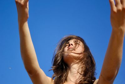 Low angle portrait of woman against blue sky