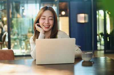 Portrait of young woman using laptop while sitting on table