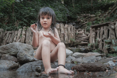 Portrait of shirtless boy sitting on rock