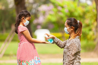 Mother giving sanitizer to daughter in park
