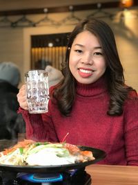 Portrait of smiling woman holding glass at restaurant