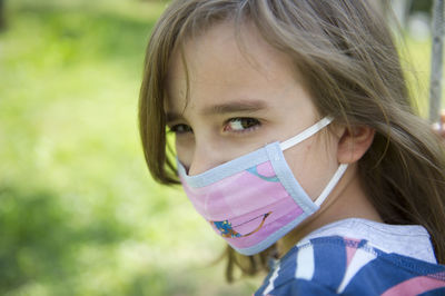 Close-up portrait of a girl with medical mask in the garden