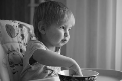 Close-up portrait of cute boy in bowl at home