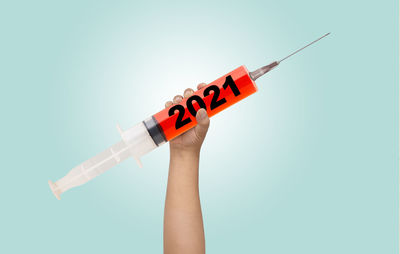 Close-up of hand holding flag against colored background