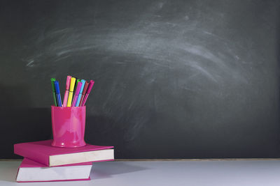 Close-up of multi colored pencils on table against wall