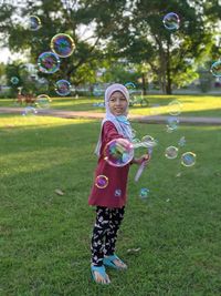 Full length of girl playing with bubble  at park