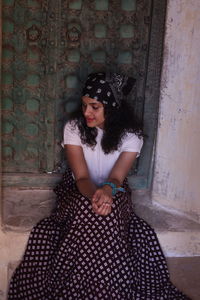 Curly hair girl sitting at the doorway in front of the rusty old entrance inside a castle in india