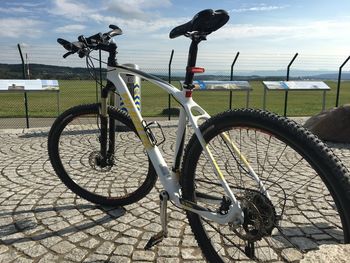 Bicycle parked on street by sea against sky