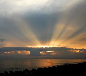 Scenic view of sea against cloudy sky at sunset