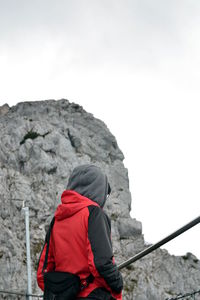 Low angle view of hooded woman standing against mountain