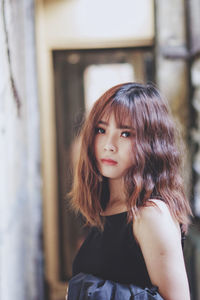 Portrait of beautiful woman standing against wall