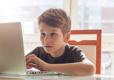 Boy using laptop at table