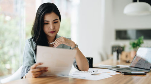 Portrait of young woman using laptop while sitting on table