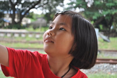 Girl looking away against trees