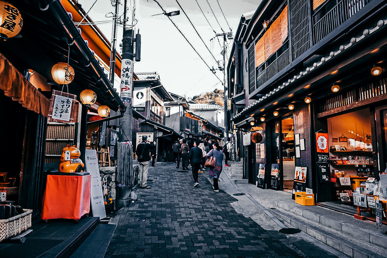 PEOPLE WALKING ON STREET AMIDST BUILDINGS