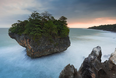 Rock formation by sea against sky during sunset